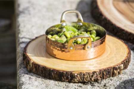 kleiner Kupfertopf auf Holzscheibe