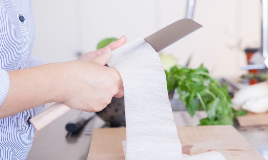 Frau schneidet Küchenpapier mit Messer