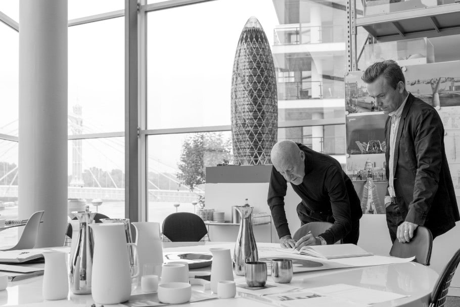 Norman Foster über Tisch gebeugt